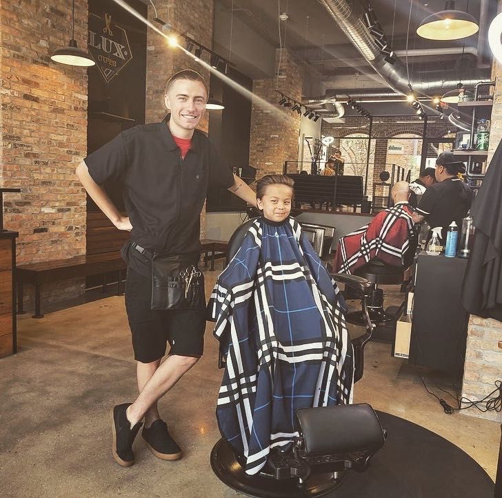 A Lux Cuts barber with a young client in the shop